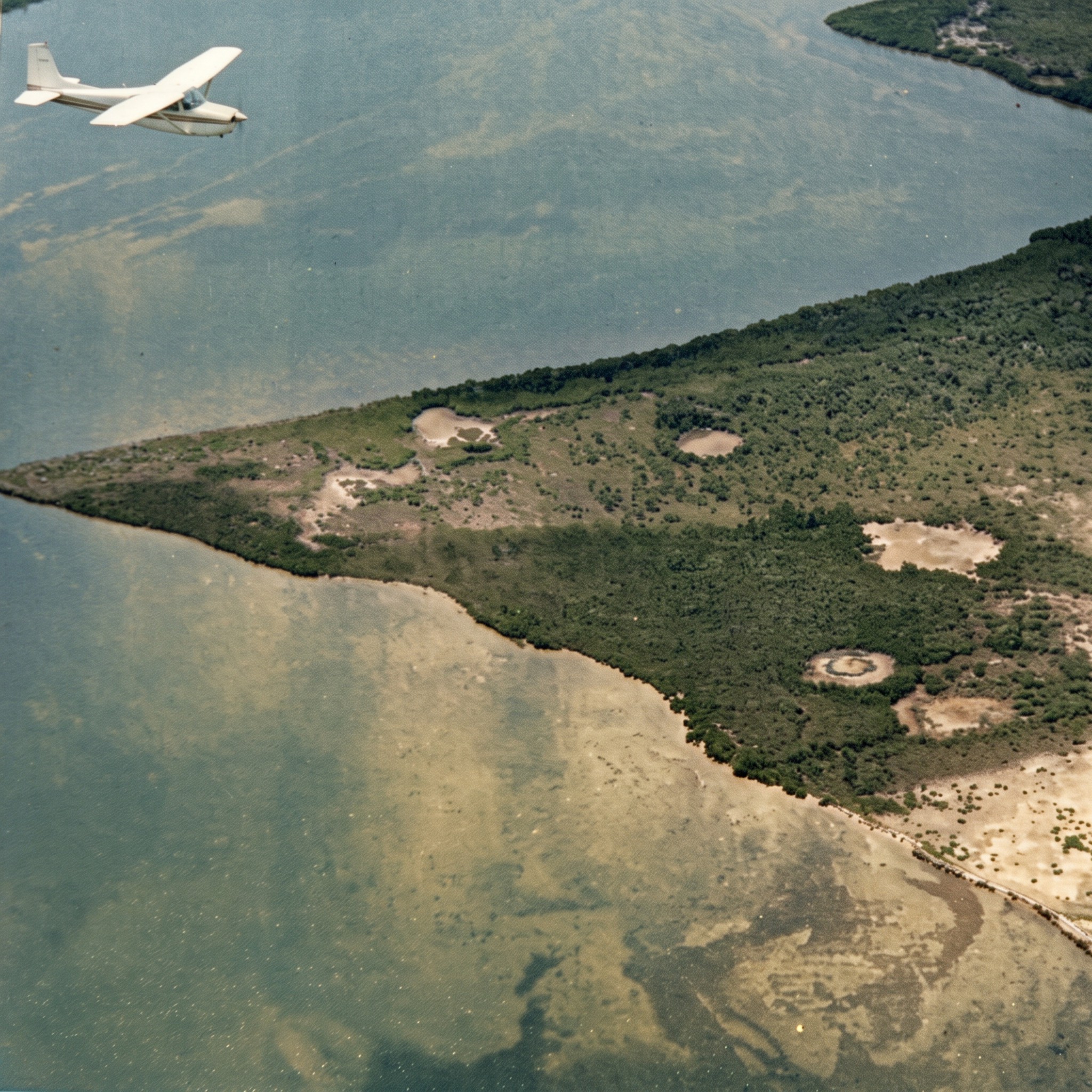 Colorized 1957 aerial photo of a small Cessna airplane flying over Redfish Point on the Caloosahatchee River, where Cape Coral was built