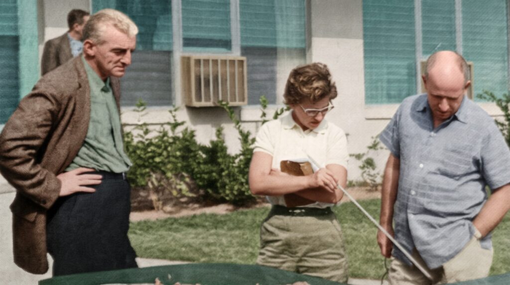 Colorized 1958 photo of Cape Coral designer Milt Mendelsohn and a Gulf American executive showing the city plan to radio host Galen Drake outside the first sales building